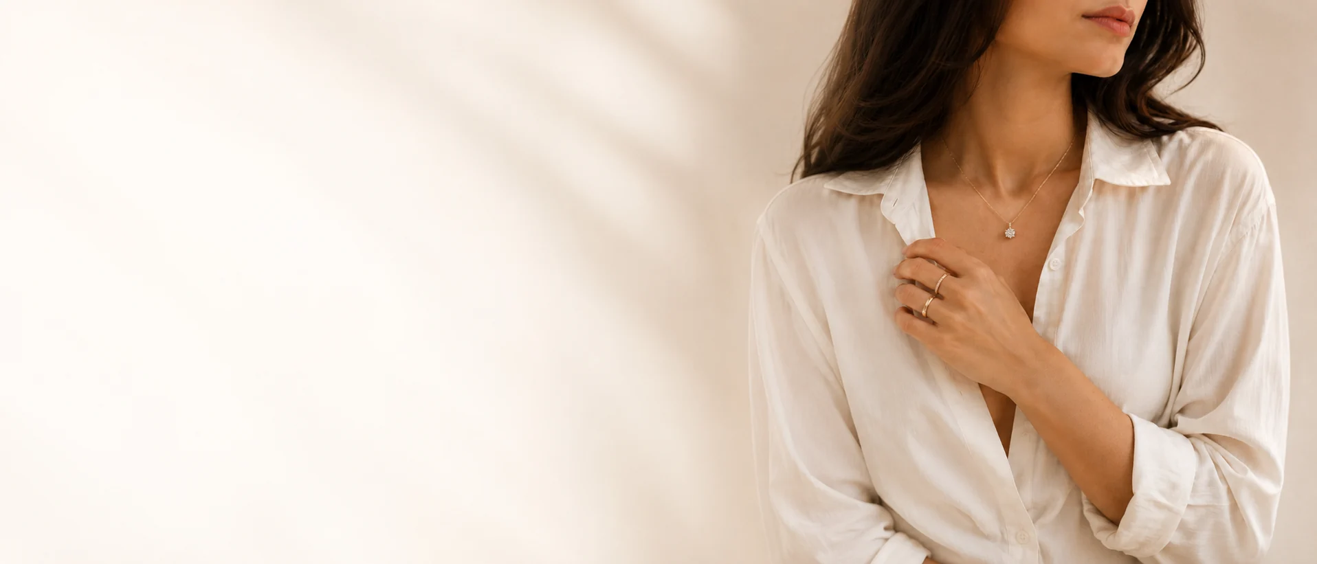 Woman wearing a delicate necklace in a quiet everyday setting.